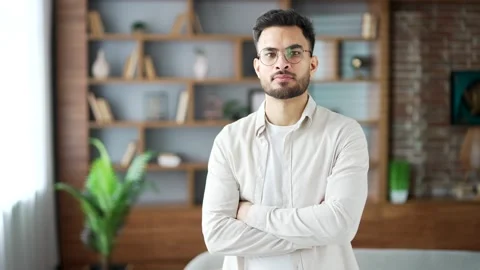 Portrait of confident serious young man wearing glasses stands with arms crossed Stock Footage 296579180