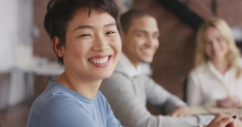 Portrait of a confident young Asian business woman at boardroom table in office Stock Footage