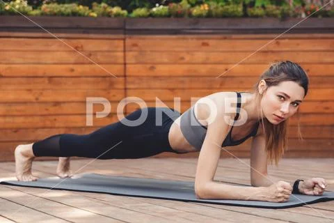 Portrait of a confident young fitness girl doing plank exercise Stock Photos