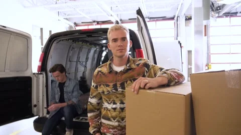 Portrait confident young man at back of moving van in storage facility 動画素材 221037918
