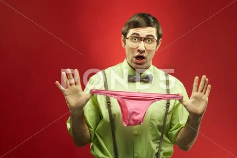 Portrait of confused nerd holding panties Stock Photos