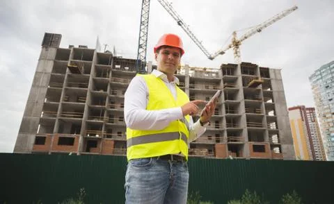 Portrait of construction engineer in hardhet using digital tablet on building Stock Photos