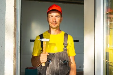 Portrait of construction worker in red cap holding hammer, ready for carpen.. Stock Photos