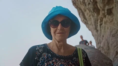Portrait of contented and happy elderly woman standing on hiking trail in cliff Stock Footage 201261374
