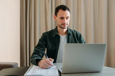Portrait of a contented young man using a laptop at a table in office or at h Foto stock
