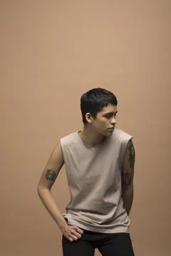 Portrait of cool young nonbinary man with tattoos in tank top Stock Photos