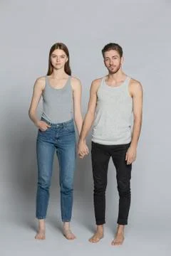 Portrait of couple holding hands while standing against gray background Stock Photos