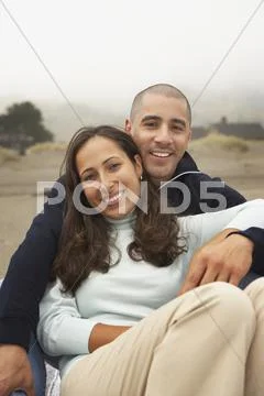 Portrait of couple sitting together at beach Stock Photos