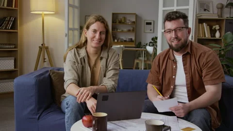 Portrait Couple Smiling at Camera with Open Laptop and Documents on Table Stock Footage 327685140