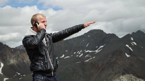 Portrait of courageous man with a backpack sitting on the edge of rock, looking Stock Footage 65483514
