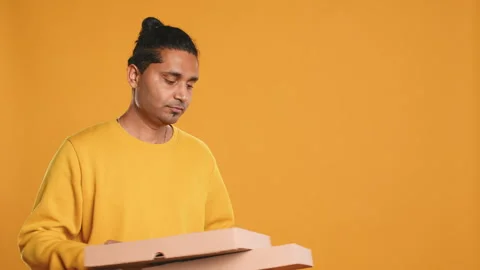 Portrait of courier carrying stack of pizza boxes, studio background Video stock 274332382