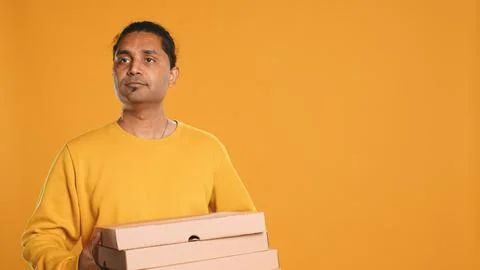 Portrait of courier carrying stack of pizza boxes, studio background Stockfoto's