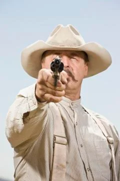 Portrait of a cowboy aiming his gun ready to shoot Stock Photos