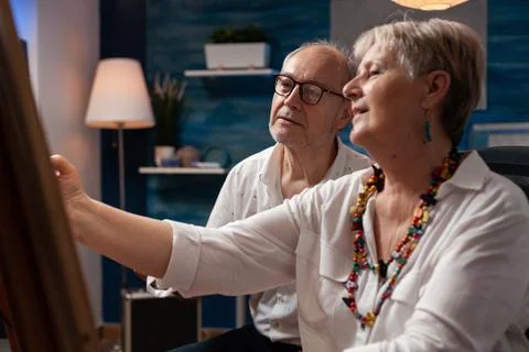 Portrait of creative elderly couple drawing in pencil sitting down in front of Stock Photos