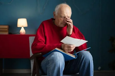 Portrait of crying elderly man holding photo from album with retro photogra.. Stock Photos