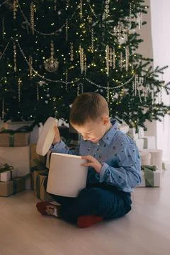 Portrait of curious boy looking inside big giftbox on Christmas evening Stock Photos