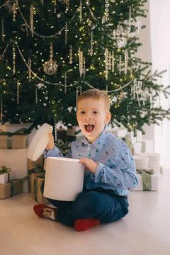 Portrait of curious boy looking inside big giftbox on Christmas evening Stock Photos