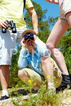 Portrait of curious lad looking through binoculars with his parents near by Stock Photos