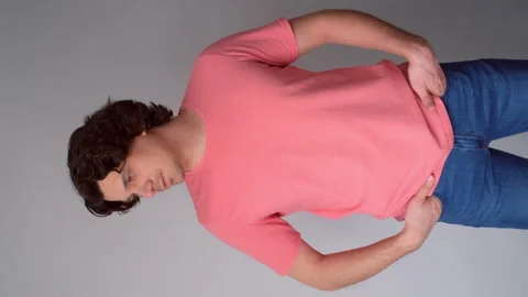 Portrait curly brunet model man in jeans pink t-shirt posing on gray background. Stock Footage 311873797