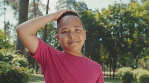 Portrait of cute boy looking into camera, smiling charmingly outdoors Stock Footage 159795388