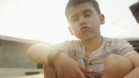 Portrait of a cute boy looking at the camera against sunset at home. Stock Footage 245751971
