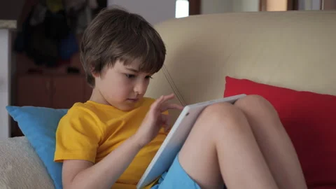 Portrait of Cute Boy Playing Game on Tablet PC Relaxing in Living Room. Child Stock Footage 245559248