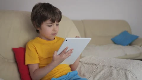 Portrait of Cute Boy Playing Game on Tablet PC Relaxing in Living Room. Chi.. Stock Footage 303907754