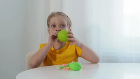 Portrait of a cute charming girl inflating a green balloon. Lung training. Child 스톡 동영상 185653853