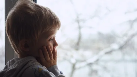 Portrait of cute child sits on the window-sill and looking out the window  Stock Footage 100304053