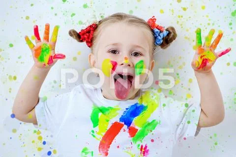 A portrait of a cute girl in colorful paints. Childhood, leisure activities. Stock Photos