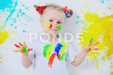 A portrait of a cute girl in colorful paints. Childhood, leisure activities. Stock Photos
