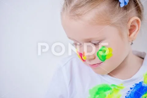 A portrait of a cute girl in colorful paints. Childhood, leisure activities. Stock Photos