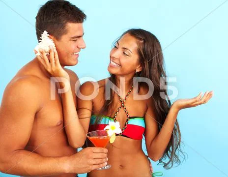 Portrait of cute girl placing seashell against the ear of handsome man with cock Stock Photos