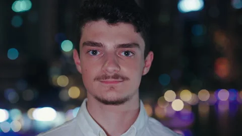 Portrait of Cute Guy Turning Head to the Camera, on Night City Background. Close Stock Footage 256143240