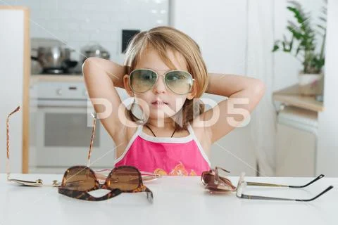 Portrait of cute little girl trying to wear glasses Stock Photos