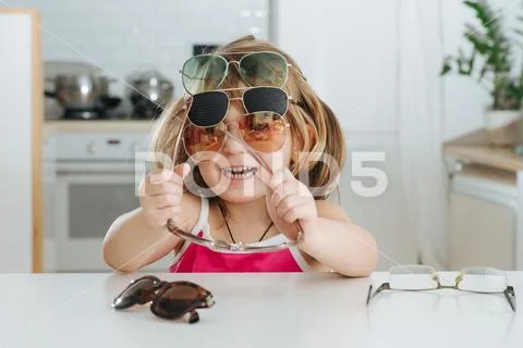 Portrait of cute little girl trying to wear glasses Stock Photos
