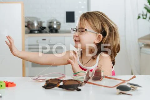 Portrait of cute little girl trying to wear glasses Stock Photos