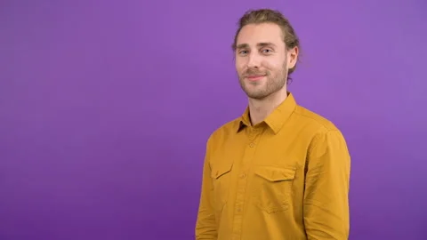 Portrait of cute long haired man smiling on isolated purple background. the man Stock Footage 145477494