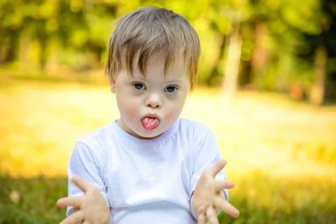 Portrait of Cute small boy with Down syndrome playing in nature Stock Photos