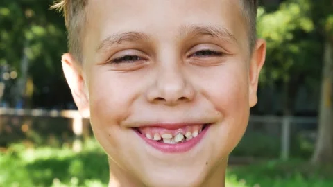 Portrait of a cute smiling boy of 7-8 years old against the background of green Stock Footage 230180297