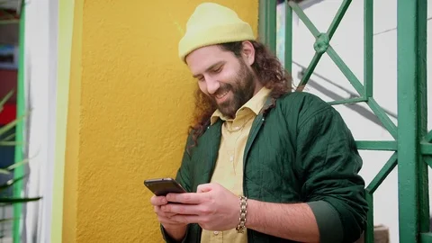 Portrait of cute smiling Hispanic man using black phone device chatting outdoor Stock Footage 108428567