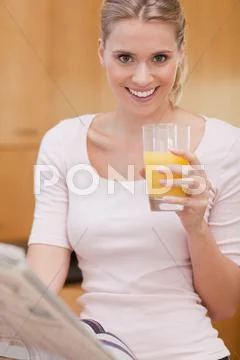 Portrait of a cute woman reading the news while drinking juice Stock Photos