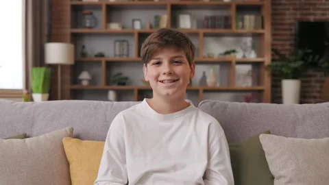 Portrait of cute young boy looking at camera sitting on a coach. Smiling Stock Footage 245728322
