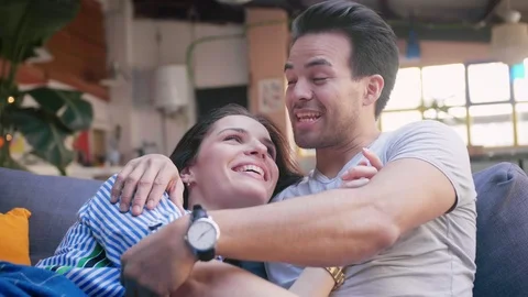 Portrait of cute young Hispanic couple spend lovely time together on cozy grey Stock Footage 105756827