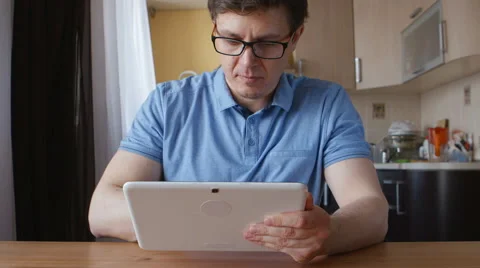 Portrait of a cute young man with a tablet PC at the table Stock Footage 60570817