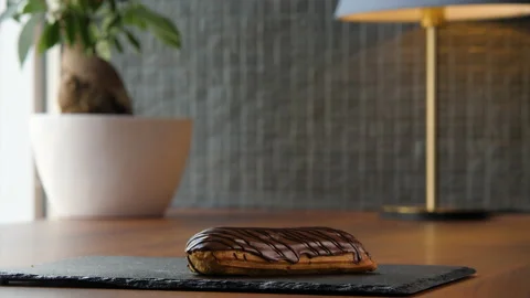 Portrait of a delicious eclair covered with chocolate glaze 스톡 동영상 168188301