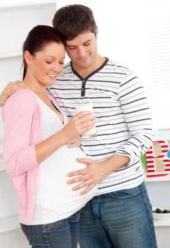 Portrait of a delighted pregnant woman holding a glass of milk and of her hus Stock Photos
