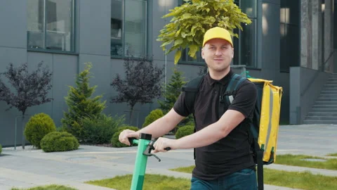 Portrait of delivery man standing with electric scooter with yellow thermal Stock Footage 172012889