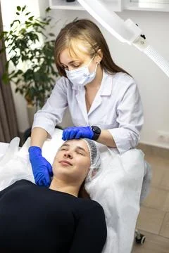 Portrait of a dermatologist preparing her client for a cosmetic treatment. The Stock Photos