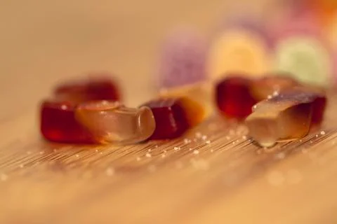 A portrait of different pieces of colorful candy lying on a wooden table with Stock Photos